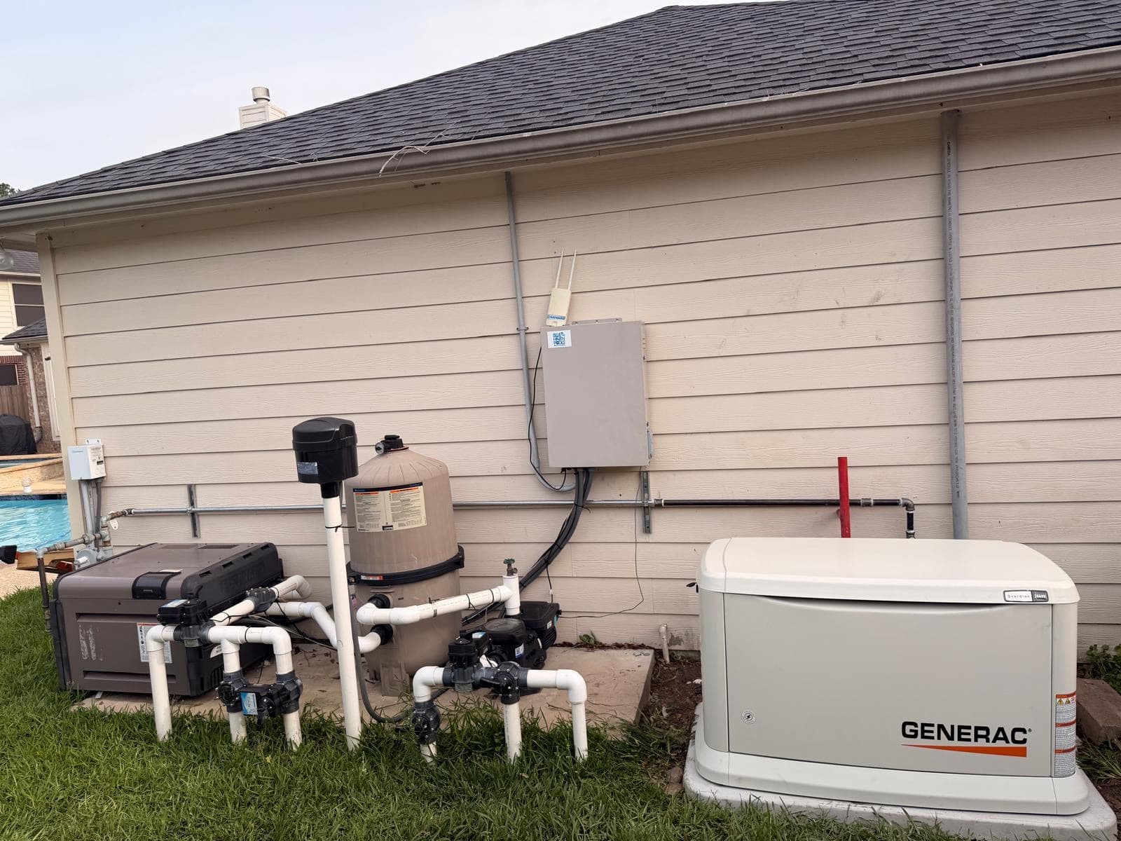 Completed Generac standby generator on a concrete pad beside a house, wired to an exterior disconnect